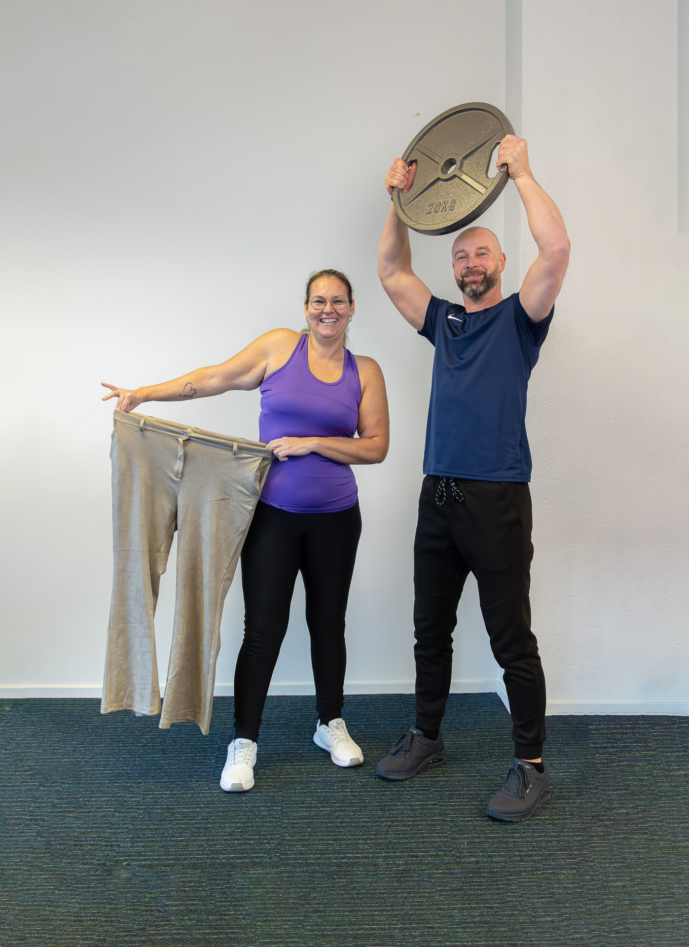 Wendy met haar oude broek na 20 kilo afvallen, naast haar trainer
